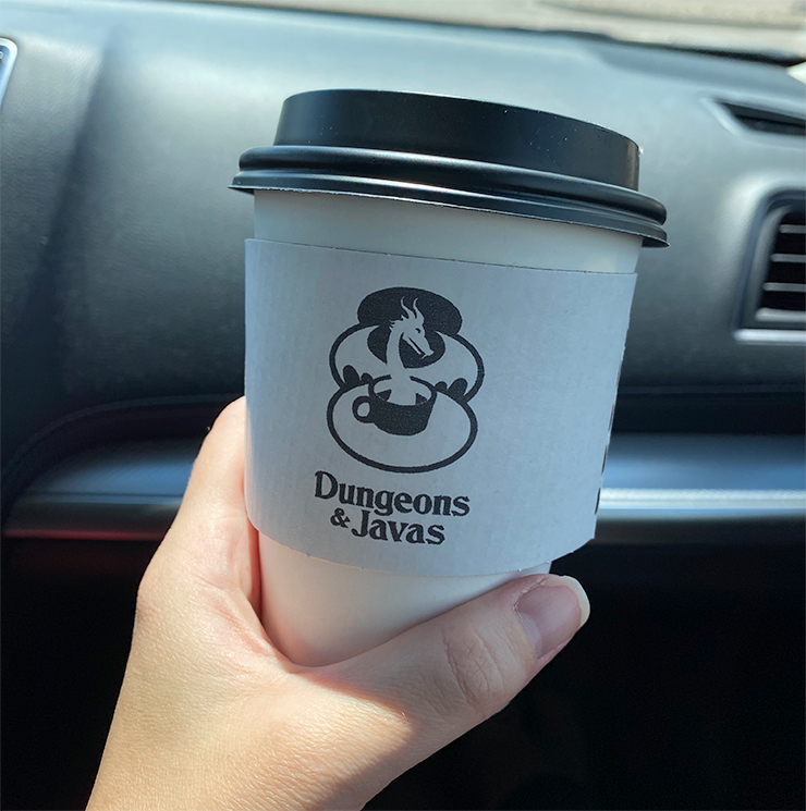 Coffee Cup with Dungeons & Javas Logo, a Friendly Red Dragon Emerging Like Steam From a Coffee Cup